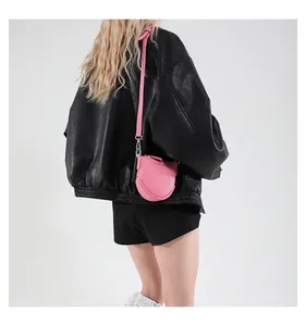 Vue arrière d'un mini sac bandoulière rose en cuir porté avec une veste en cuir noir