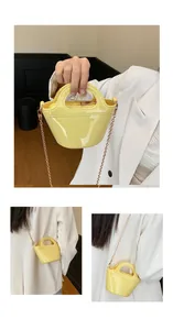 Detail of a shiny yellow leather handbag with gold chain strap and curved handle
