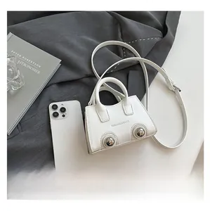Mini white PU crossbody bag with silver buckles shown next to a smartphone for size scale