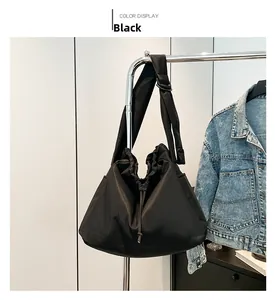 Detail of black nylon drawstring crossbody bag with pleated texture and wide strap