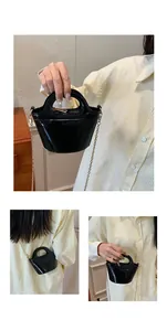 Detail of black glossy mini bucket bag with gold chain strap and rigid top handle