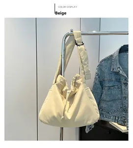 Detail view of the beige nylon drawstring bag featuring an adjustable wide shoulder strap