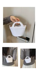 Close-up of a white glossy jelly bucket bag featuring a gold chain strap and top handle