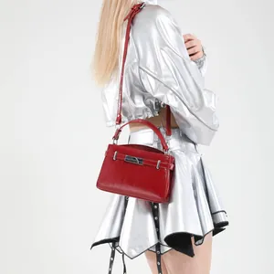 Glossy red Kelly style handbag with silver buckle and top handle shown on fashion model