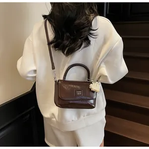Detail of chocolate brown leather crossbody bag with braided handle and pearl heart charm