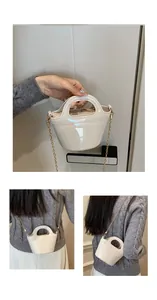 Close-up of cream glossy patent leather bag with gold chain strap and smooth handle