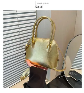 Détail d'un sac à main doré en cuir grainé avec doubles poignées et bandoulière fine