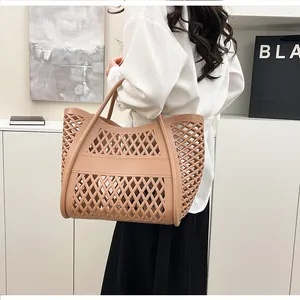Close-up of diamond cut-out pattern on skin-pink silicone tote bag held by model