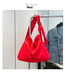 Detail of red drawstring tote bag with wide shoulder strap shown on a hanger