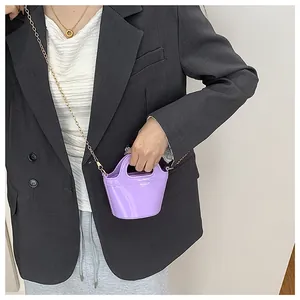 Detail of purple jelly bucket bag with gold chain strap on grey blazer outfit