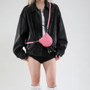 Sac bandoulière rose en demi-lune avec veste en cuir oversize noire pour un look tendance