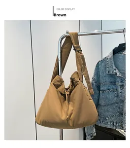 Detail of a brown puffer nylon crossbody bag featuring drawstring closure and wide strap