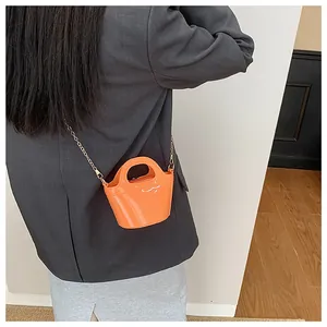 Close-up of bright orange jelly bucket bag with sleek gold chain and glossy finish