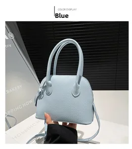 Détail du sac à main bleu clair avec texture en cuir grainé et doubles poignées