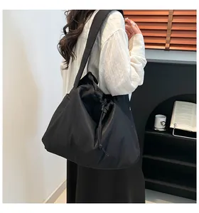 Detail view of large black drawstring tote bag in nylon fabric with wide shoulder strap