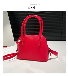 Détail du sac rouge en cuir grainé avec double poignée et finitions métalliques