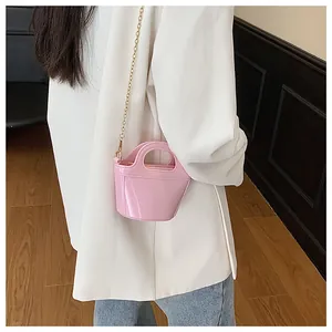 Detailed shot of a pink mini jelly bucket bag with gold chain strap on a model