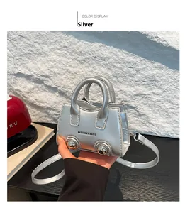 Detail of silver mini crossbody bag featuring metallic ball accents and fashion text