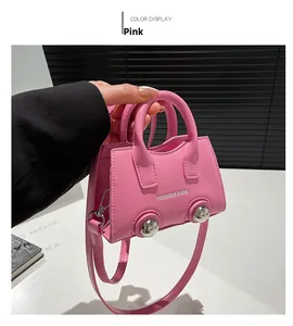 Pink mini crossbody bag with top handles and fashion text detail on plain background