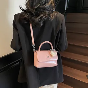 Pink glossy leather handbag with pearl heart charm shown on model in a stylish setting