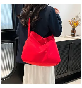 Close-up of red ruched drawstring tote bag worn over the shoulder by a model