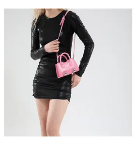 Close-up of pink leather handbag with silver studs and adjustable shoulder strap