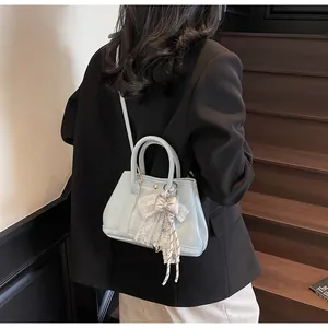 Detail of light blue handbag featuring delicate lace trim and a decorative bow accessory