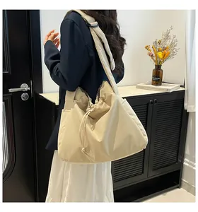 Detailed view of cream nylon tote bag with drawstring closure and wide shoulder strap