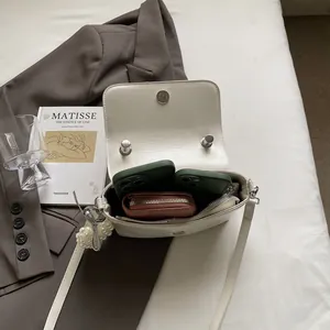 Chic beige crossbody bag with pearl charm showing interior storage for phone and wallet