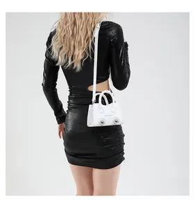 Detailed back view of mini white shell bag with silver metal spheres on black dress