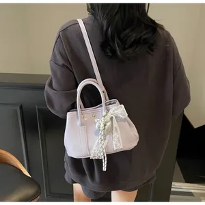 Detail of lilac faux leather bag with white lace bow and silver tassel pendant