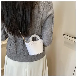 Close-up of a white mini jelly bag with golden chain strap on a model wearing a grey sweater