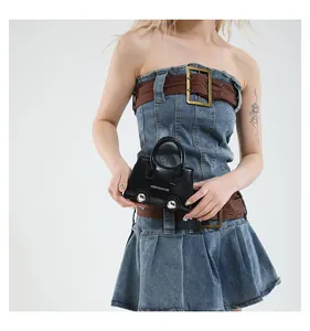 Close-up of black leather mini handbag with silver metal ball detail on denim dress