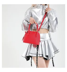 Détail du sac coquille en cuir rouge à motif litchi avec bandoulière réglable
