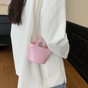 Chic pink jelly handbag with gold chain strap worn as a stylish crossbody shoulder bag