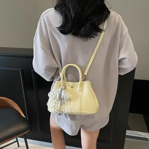 Minimalist yellow handbag with lace bow and heart charm worn by a fashion model