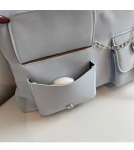 Detail of light blue crossbody bag featuring functional pockets and silver chain accents