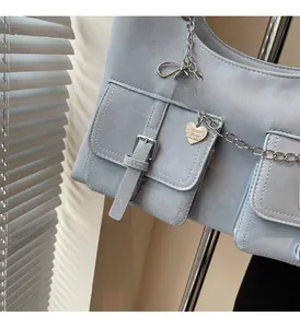 Detail of light blue glossy handbag featuring silver heart charms and metal chain strap