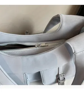 Detailed close-up showing smooth metal zipper and gray leather texture on the shoulder bag