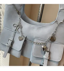Close-up of light blue matte shoulder bag with metallic chains and decorative charms
