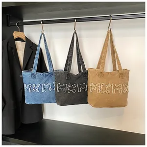 Detail van gewassen denim tote bags in blauw, zwart en geel met MKM letters met rafelranden