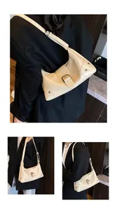 Detail view of a cream glossy leather crescent bag with silver studs and metal buckle