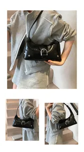 Close-up of black patent leather crescent bag with signature silver D-buckle detail