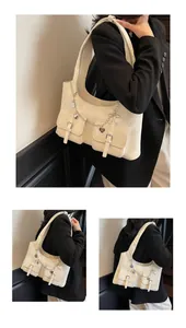 Detail of cream leather shoulder bag featuring silver chains and heart charms decoration