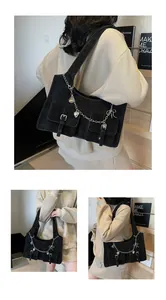 Detail of black suede shoulder bag with silver buckles and heart chain charms