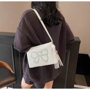 Chic cream bow shoulder bag with silver studs and lace pearl charm shown on model