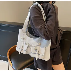 Detail of light blue crossbody bag with utility pockets, silver chains and heart charms