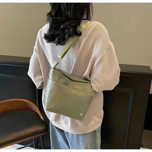 Detail of light green oxford fabric crossbody bag with wide strap on model