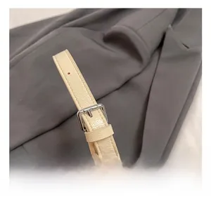 Detail of adjustable cream leather shoulder strap with polished silver metal buckle