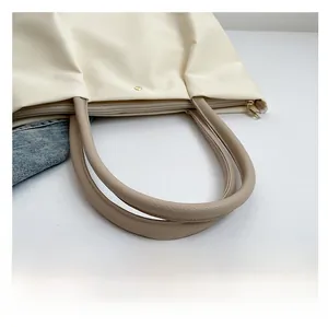 Detail of white nylon tote bag with brown litchi pattern straps and gold metal zipper